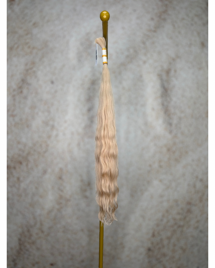 Four bundles of golden blond body wavy bulk hair arranged together.