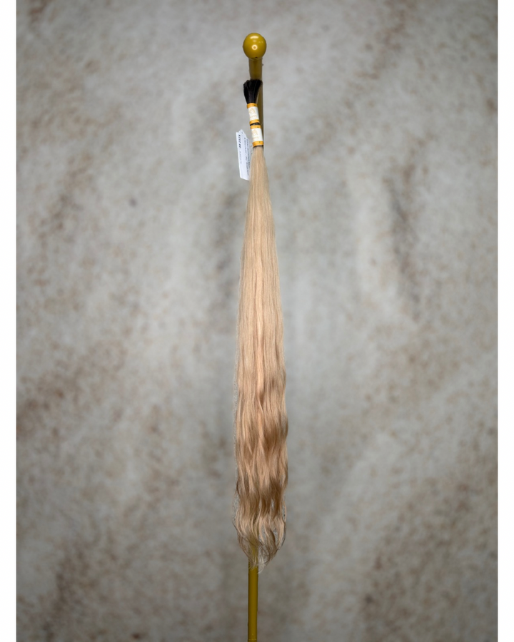 Four bundles of golden blond with dark roots body wavy bulk hair arranged together.