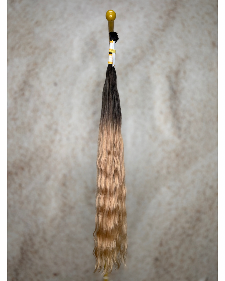 Four bundles of golden blond with deep dark roots body wavy bulk hair arranged together.